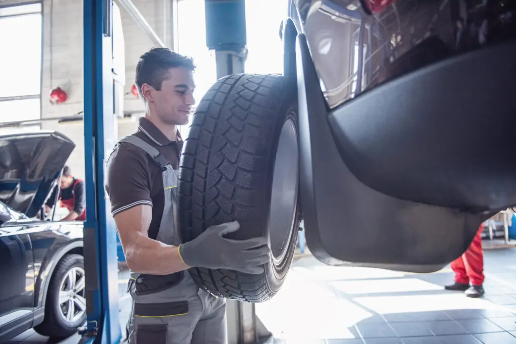 Service center technician rotating car tires.