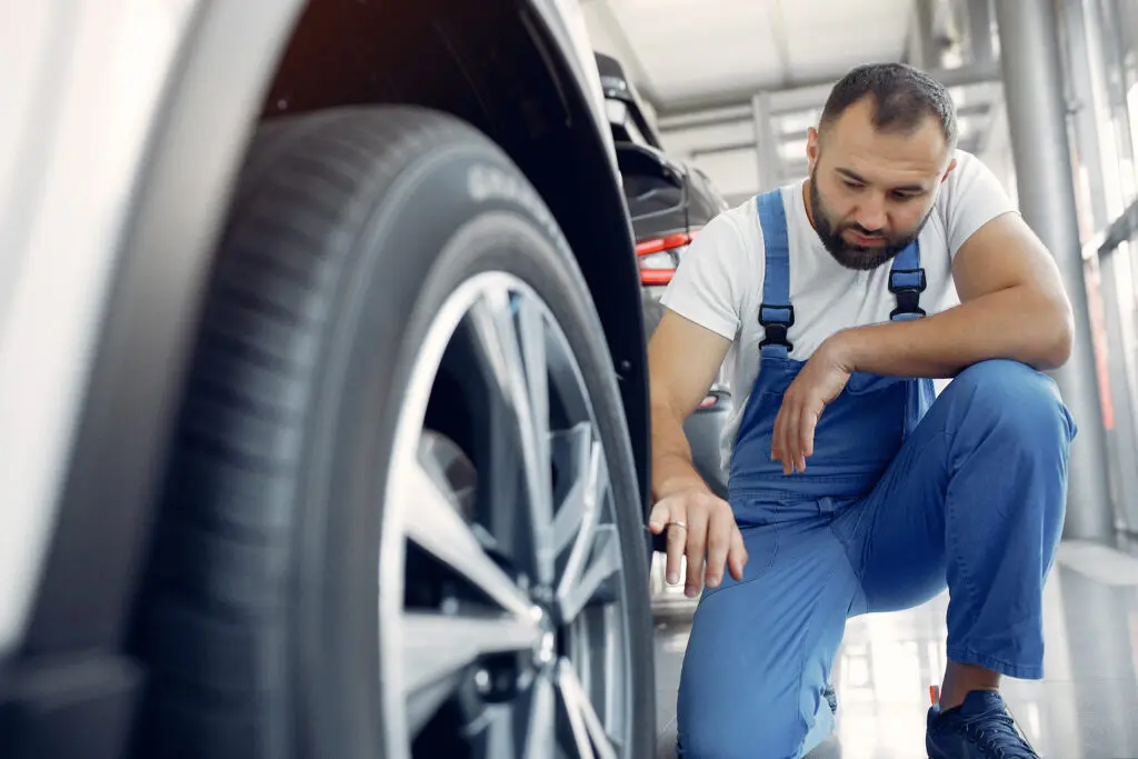 Mechanic inspecting tread wear on a tire.