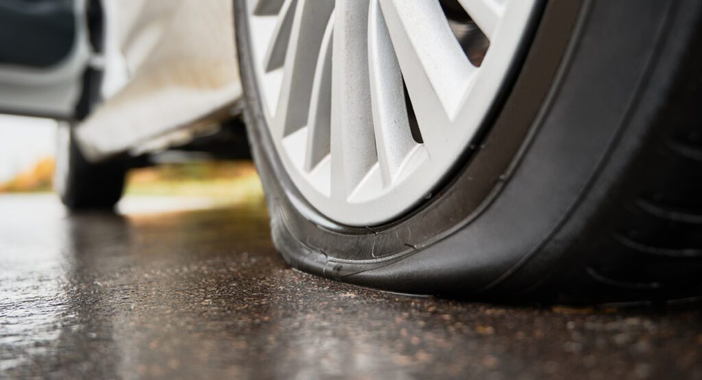 Close-up of a car wheel with a flat tire, emphasizing the need for flat tire repair.